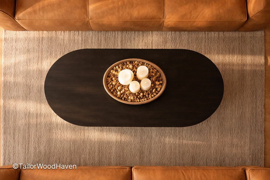 Top-down view of a black oval wooden coffee table with decorative items in a living room.