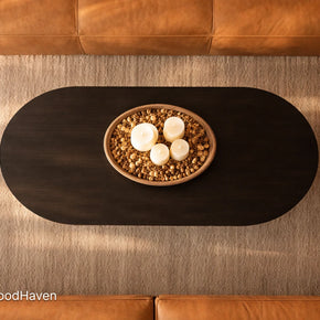 Top-down view of a black oval wooden coffee table with decorative items in a living room.