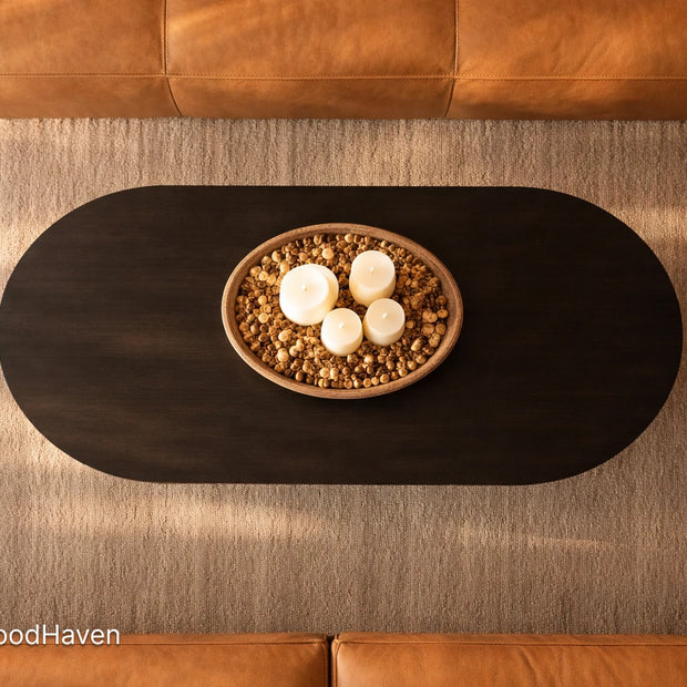 Top-down view of a black oval wooden coffee table with decorative items in a living room.