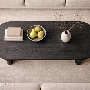 Dark wooden coffee table with decorative items on a beige carpet